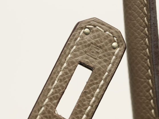 Hermès blind date stamp pressed into the strap tab of a taupe leather bag